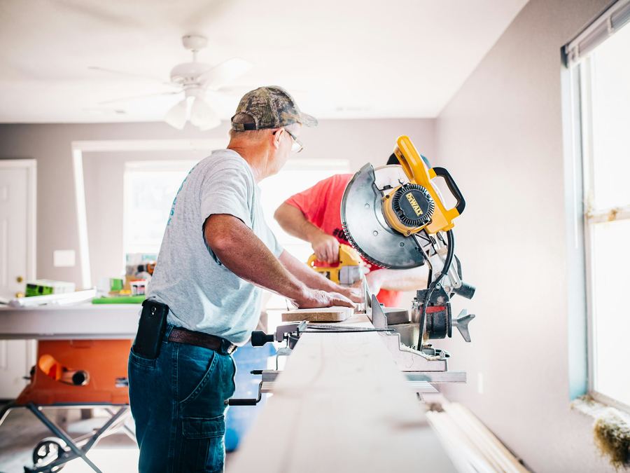 Contractors cutting trim with a miter saw during interior restoration work