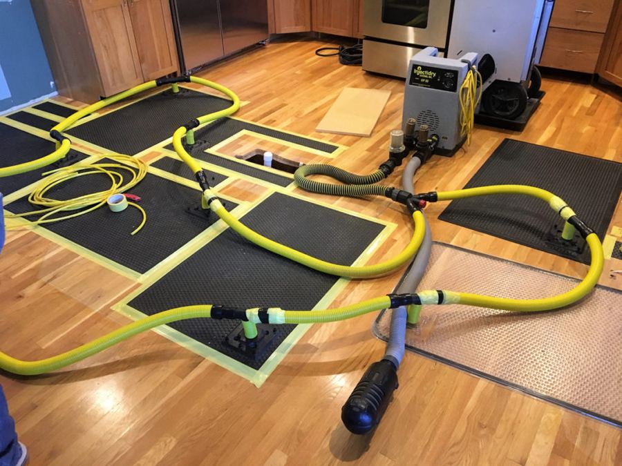 Water extraction hoses and drying mats set up on a hardwood floor